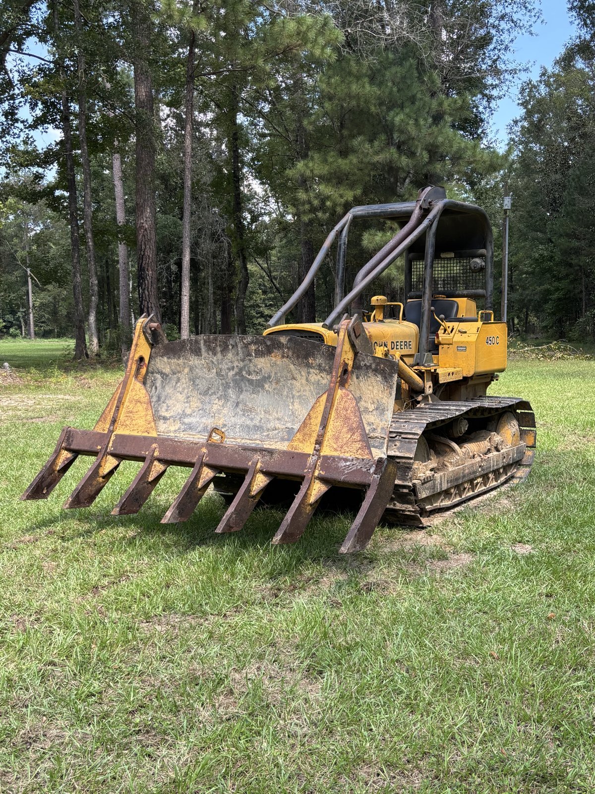 John Deere 450C dozer with root rake pushing storm debris